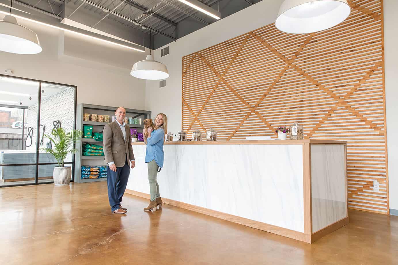 photo of Hounds Lounge owner Mandy holding a client's dog at front desk