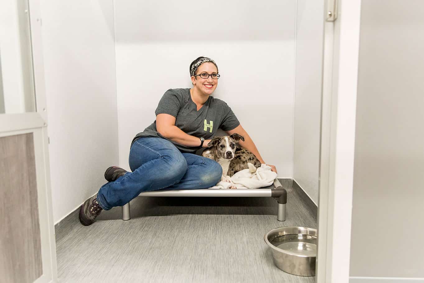 Photo of staff member sitting with puppy in orthopedic dog bed at Hounds Lounge